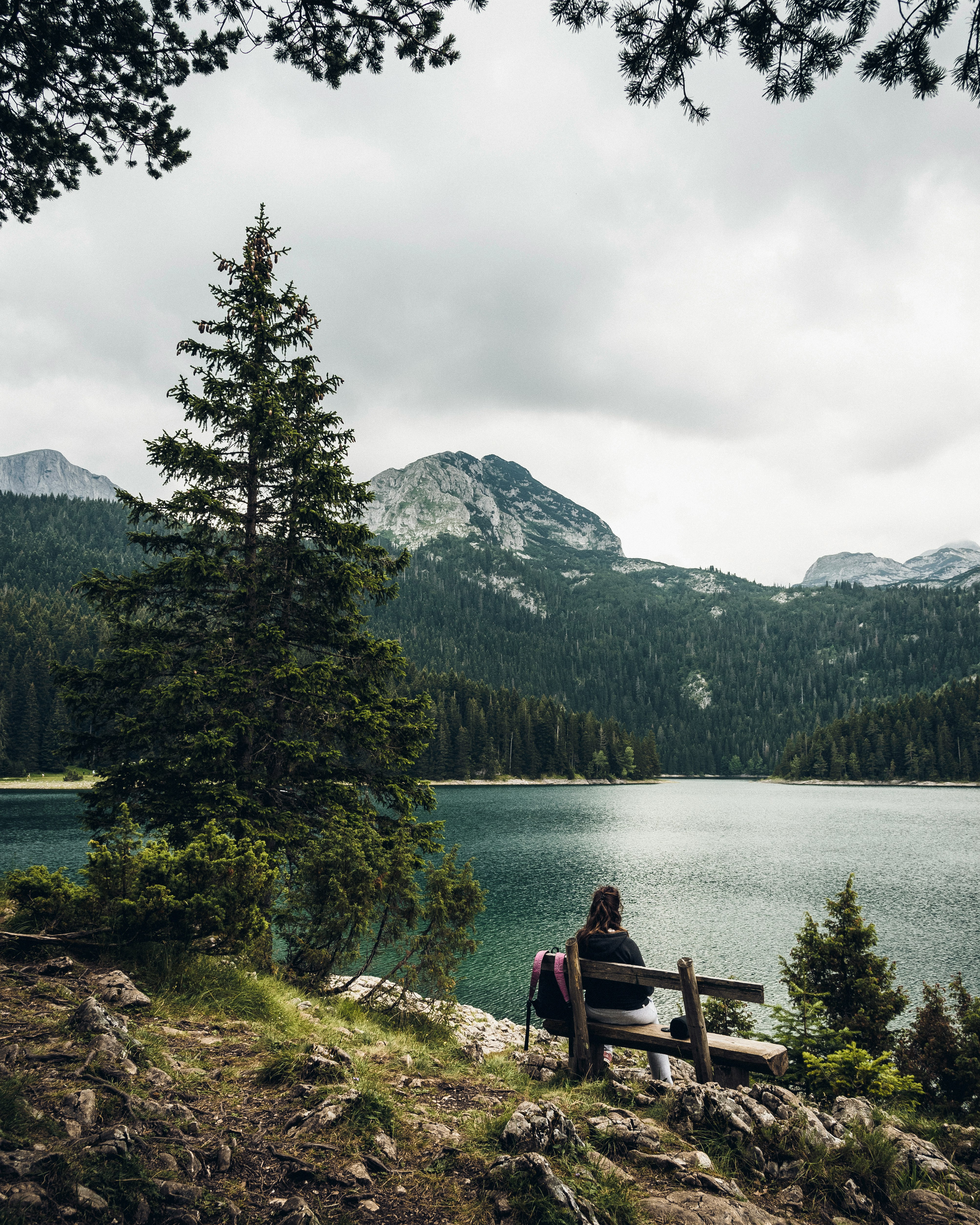 woman sitting on bench facing lake